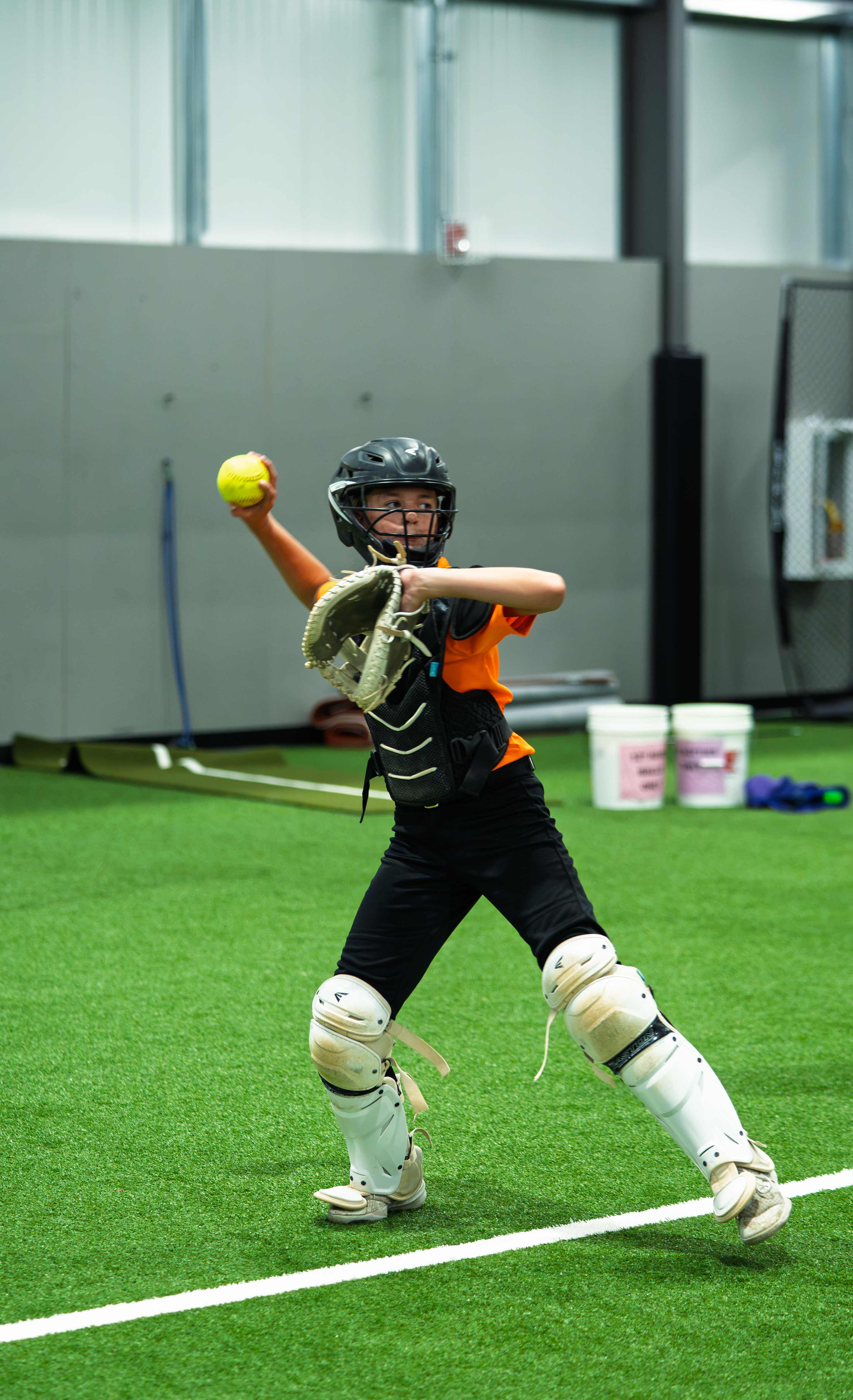 Young catcher in full gear throwing a softball